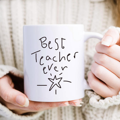 White mug with 'Best Teacher Ever' text held by hands against a neutral background | Little Heirloom