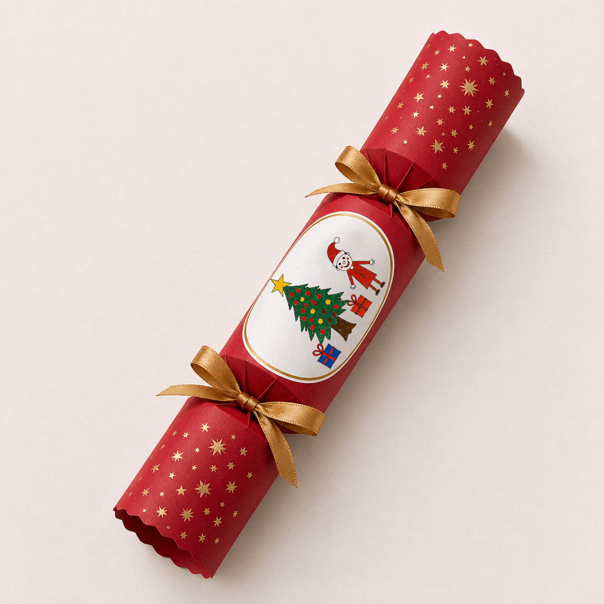 A red Christmas paper cracker with gold star patterns, tied with two gold ribbons, and featuring a child's drawing | Little Heirloom