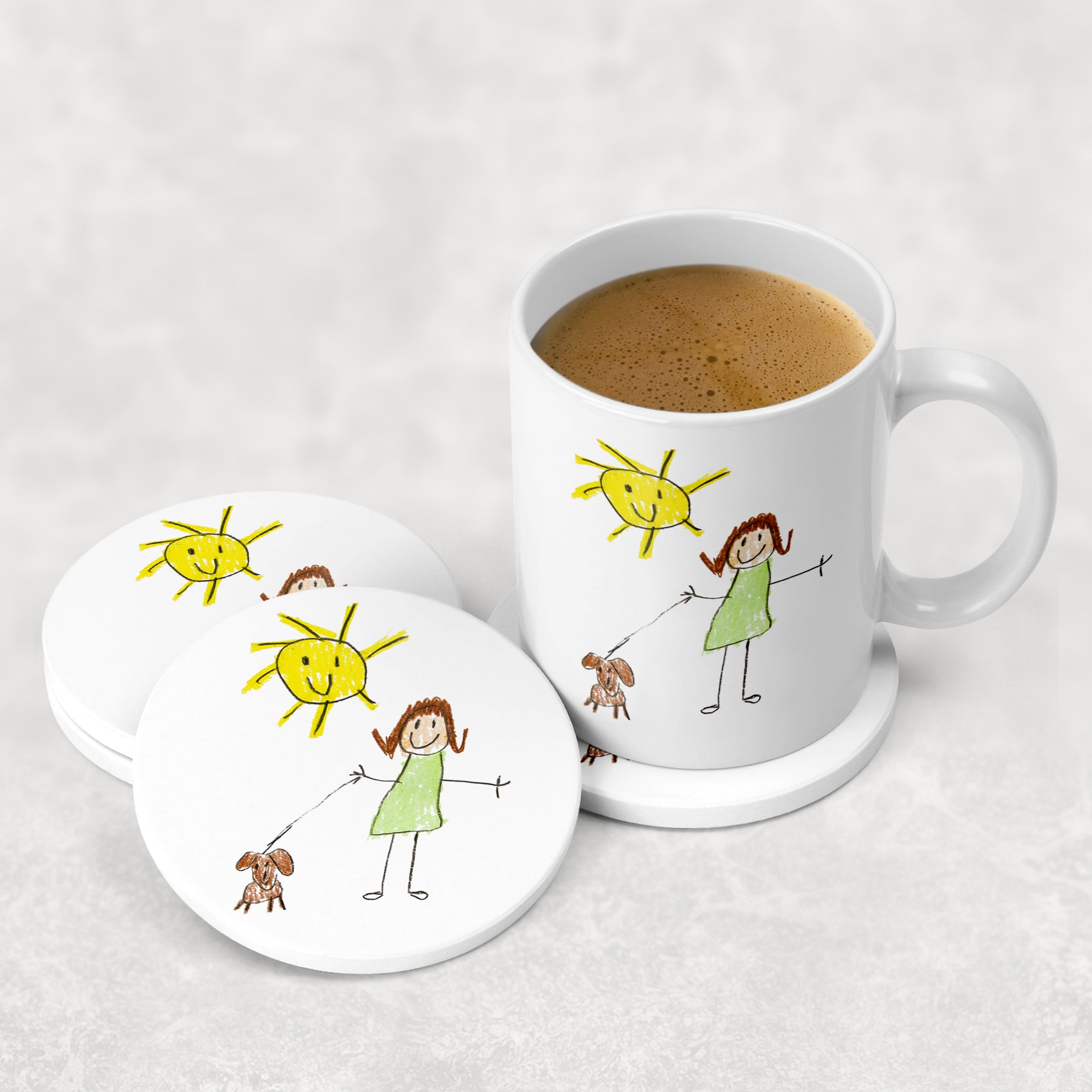 White mug with illustrations of a sun, people, and a dog, accompanied by matching coasters on a white surface.| Little Heirloom