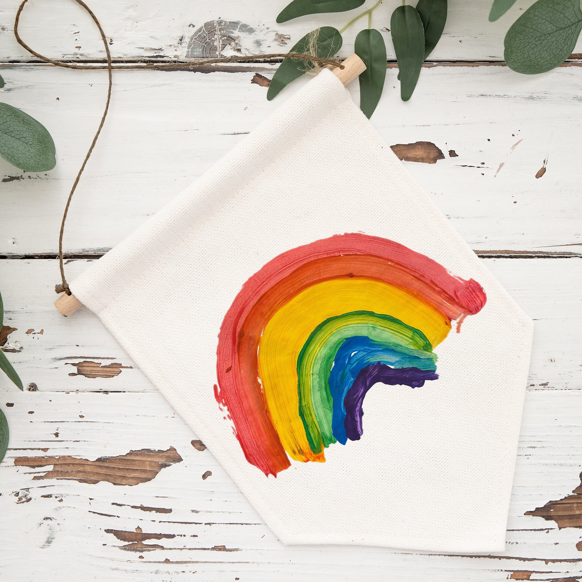 Children's drawing of a rainbow on a white sheet of paper with green leaves in the background. | Little Heirloom