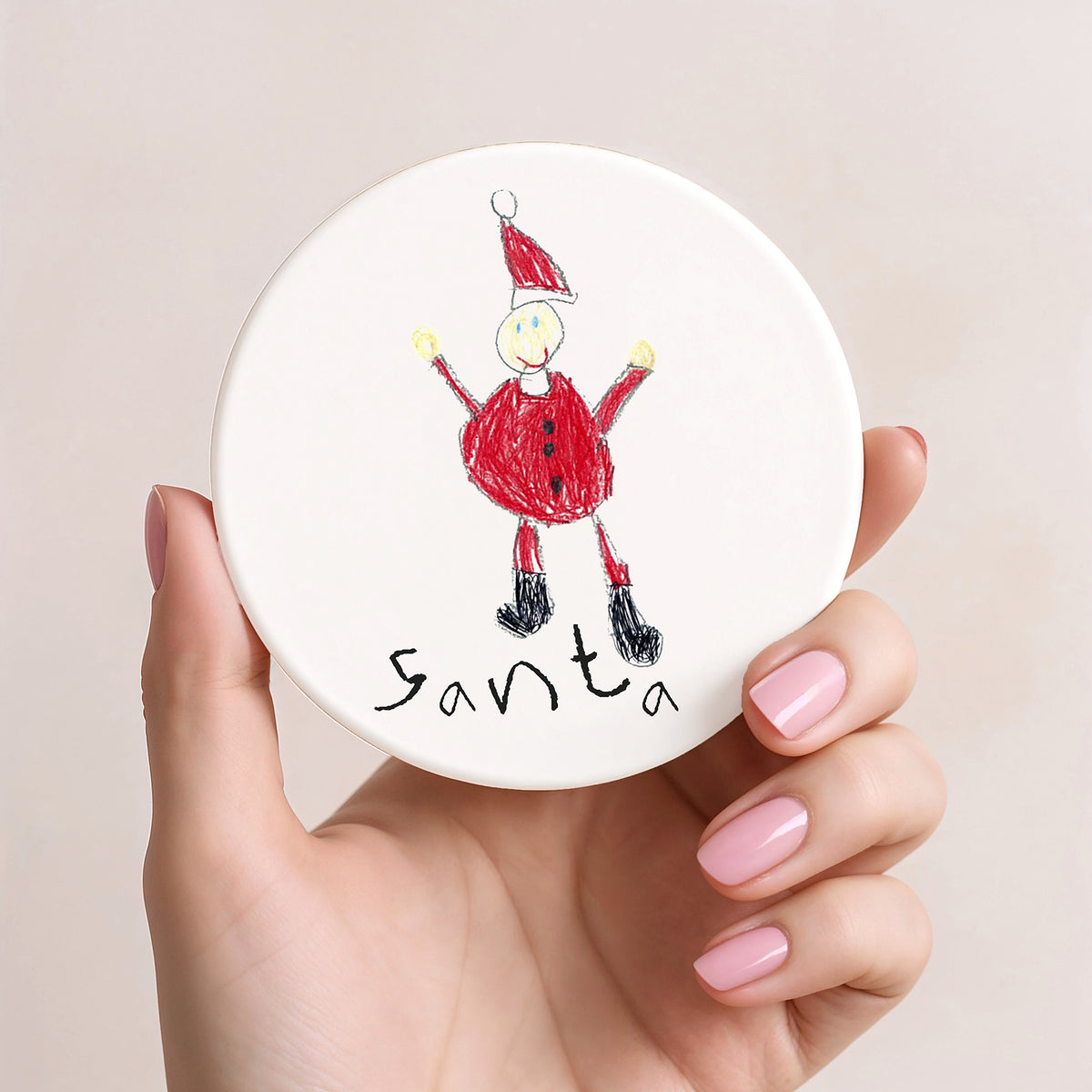Hand holding a round white coaster with a drawing of Santa Claus on a beige background | Little Heirloom